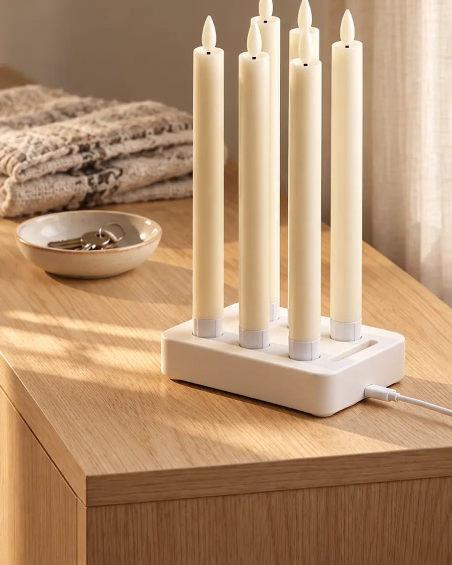 Six bougies flambeaux LED dans le socle de charge blanc sur une commode en chêne au soleil du matin