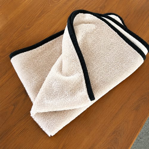 Lavette microfibre Wove beige pliée sur un plan de travail en bois