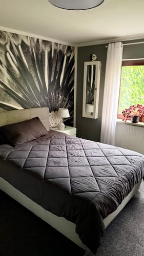Couette Wove gris anthracite sur un lit double devant un mur foncé
