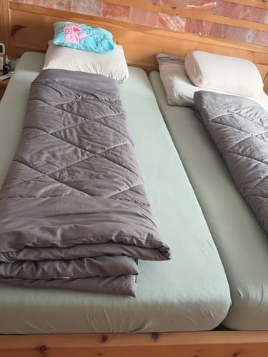Deux couettes Wove grises côte à côte sur deux matelas dans un chalet en bois