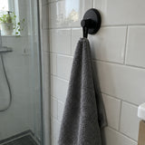 Crochet Wove noir mat sur du carrelage blanc avec une serviette grise