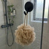 Crochet Wove noir sur une paroi de douche en verre avec une éponge beige