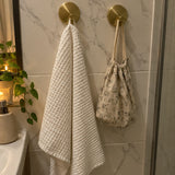 Deux crochets Wove or brossé sur du carrelage marbré avec une serviette blanche