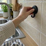 Main qui presse un crochet Wove noir sur du carrelage de cuisine beige