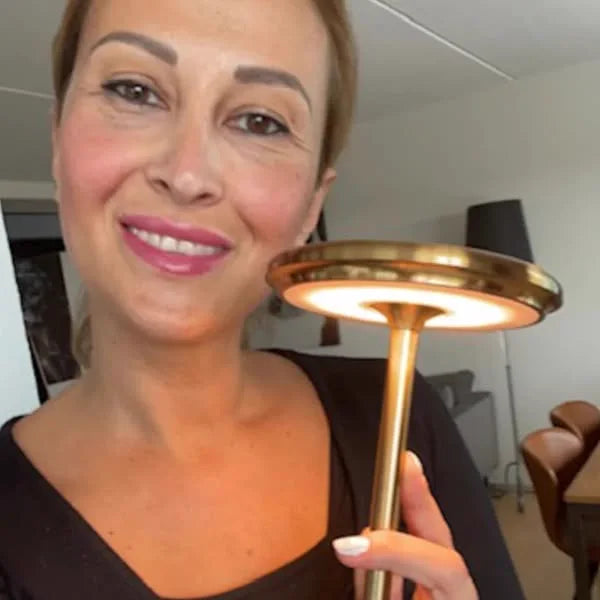 Cliente tenant la lampe Copenhagen dorée devant elle